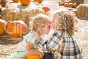 sweet little boy kisses his baby sister at pumpkin patch.