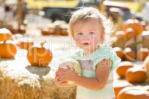 adorable baby girl holding a pumpkin at the pumpkin patch.