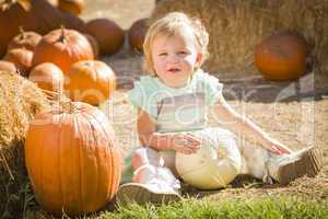 adorable baby girl holding a pumpkin at the pumpkin patch.