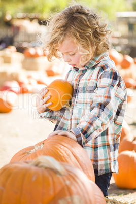 little boy holding his pumpkin at a pumpkin patch.