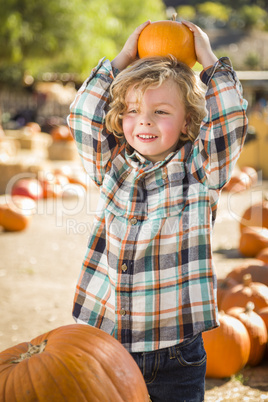 little boy holding his pumpkin at a pumpkin patch.