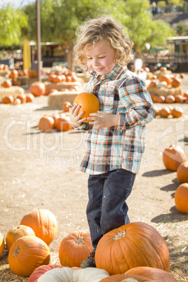 little boy holding his pumpkin at a pumpkin patch.