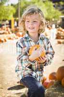 little boy holding his pumpkin at a pumpkin patch.