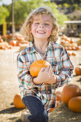 little boy holding his pumpkin at a pumpkin patch.