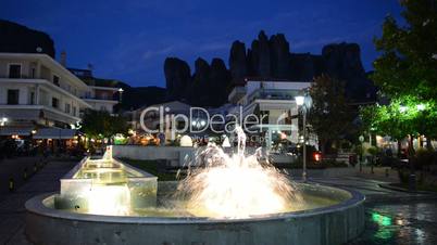 View on the fountain in Kalambaka village and Meteora mountains at background, Greece