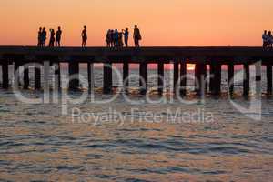 people on the old sea pier at sunset