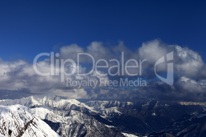 Winter sunlit mountains and sky with clouds