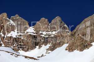 Rocks in snow and blue cloudless sky