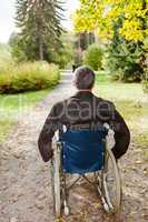 man in wheelchair in autumnal park