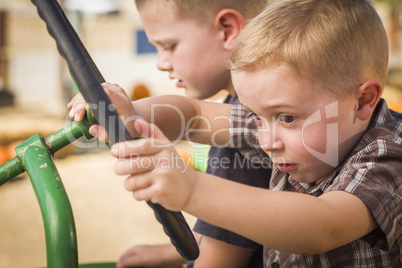 adorable young boys playing on an old tractor outside