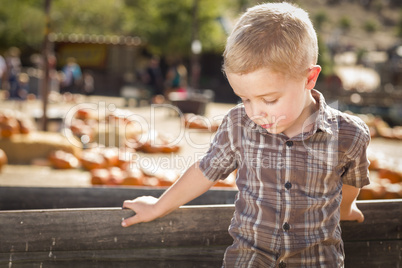 sad boy at pumpkin patch farm standing against wood wagon.