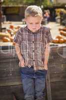 frustrated boy at pumpkin patch farm standing against wood wagon