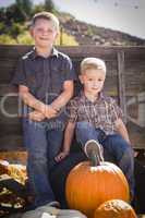 two boys at the pumpkin patch against antique wood wagon