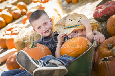 two little boys playing in wheelbarrow at the pumpkin patch.