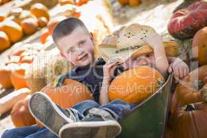two little boys playing in wheelbarrow at the pumpkin patch.