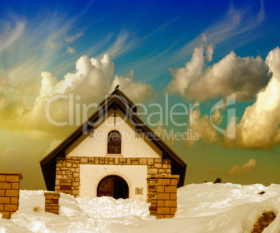 Small Church on a snowy Mountain Peak. Beautiful winter sunset c