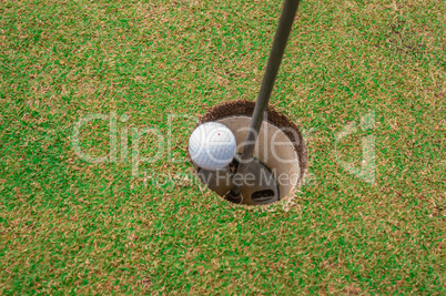 golf ball on a green, in front of the hole,