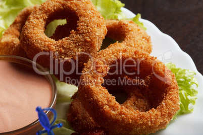 Image of meat breaded rings served with sauce
