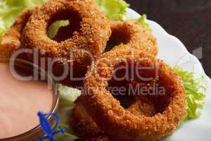 Image of meat breaded rings served with sauce