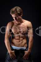 Handsome muscular blond man posing take off jeans
