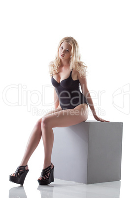 Elegant slim blonde posing in lingerie on cube