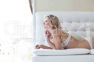 Image of pretty slim blonde lying on leather sofa