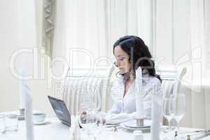 Lovely woman working at computer in restaurant