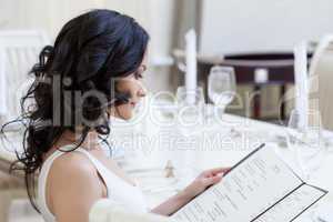 Curly young brunette choosing dishes from menu