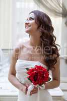 Portrait of happy bride posing with red bouquet