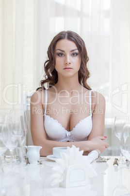 Seductive young woman posing sitting at table
