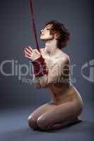 Sensual nude model posing tied with rope