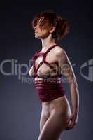 Naked red-haired woman bound in studio