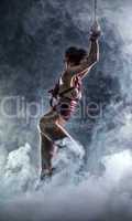 Flexible naked girl posing on smoke backdrop