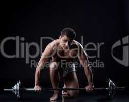 Sexual muscular guy posing with barbell in studio