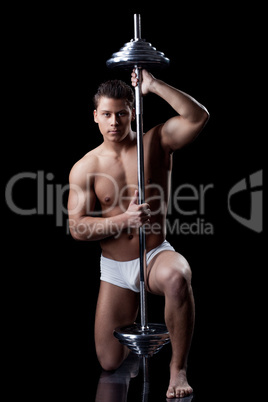 Attractive muscular man posing with barbell