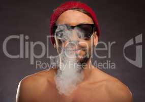 portrait of a shirtless young man blowing smoke