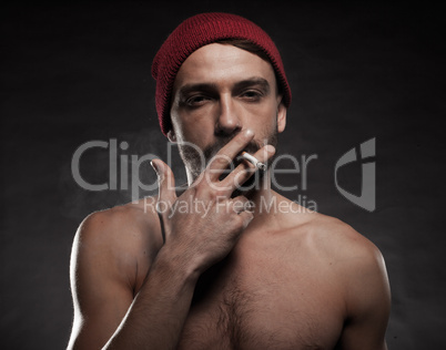 shirtless man smoking a cigarette