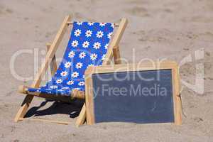 Strandliege und eine Schiefertafel am Strand