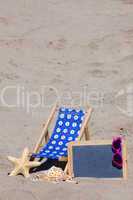 Strandliege und eine Schiefertafel am Strand