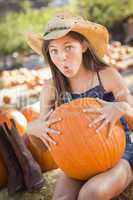 preteen girl holding a large pumpkin at the pumpkin patch.