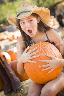 preteen girl holding a large pumpkin at the pumpkin patch.