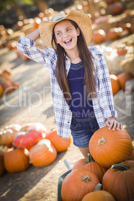 preteen girl playing with a wheelbarrow at the pumpkin patch.
