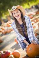 preteen girl playing with a wheelbarrow at the pumpkin patch.