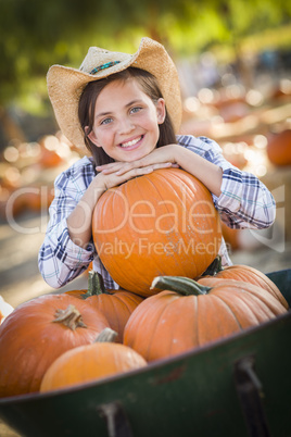 preteen girl playing with a wheelbarrow at the pumpkin patch.