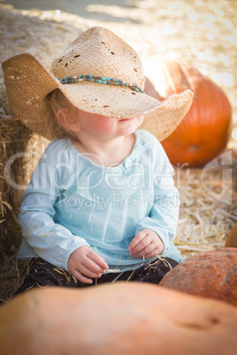 adorable baby girl with cowboy hat at the pumpkin patch.
