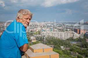the elderly man looks at a city and the river