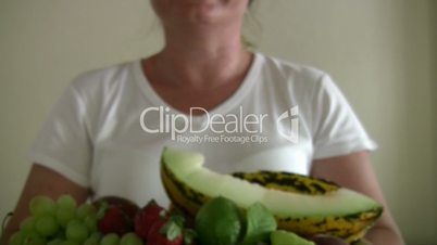 Woman showing  lots of fruits in the  dish