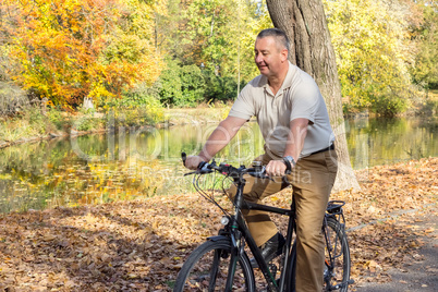 man rides his bike through the park in autumn