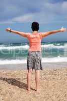 woman standing with arms outstretched on beach