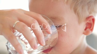 Little boy drinkng a glass of fresh water